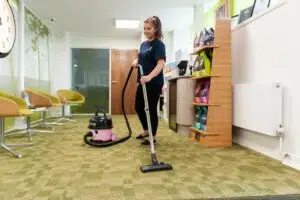 lady with a vacuum cleaner cleaning a carpet