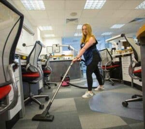 Rosie from Scott & Sons is vaccuming an office space with modern office chairs and furniture.