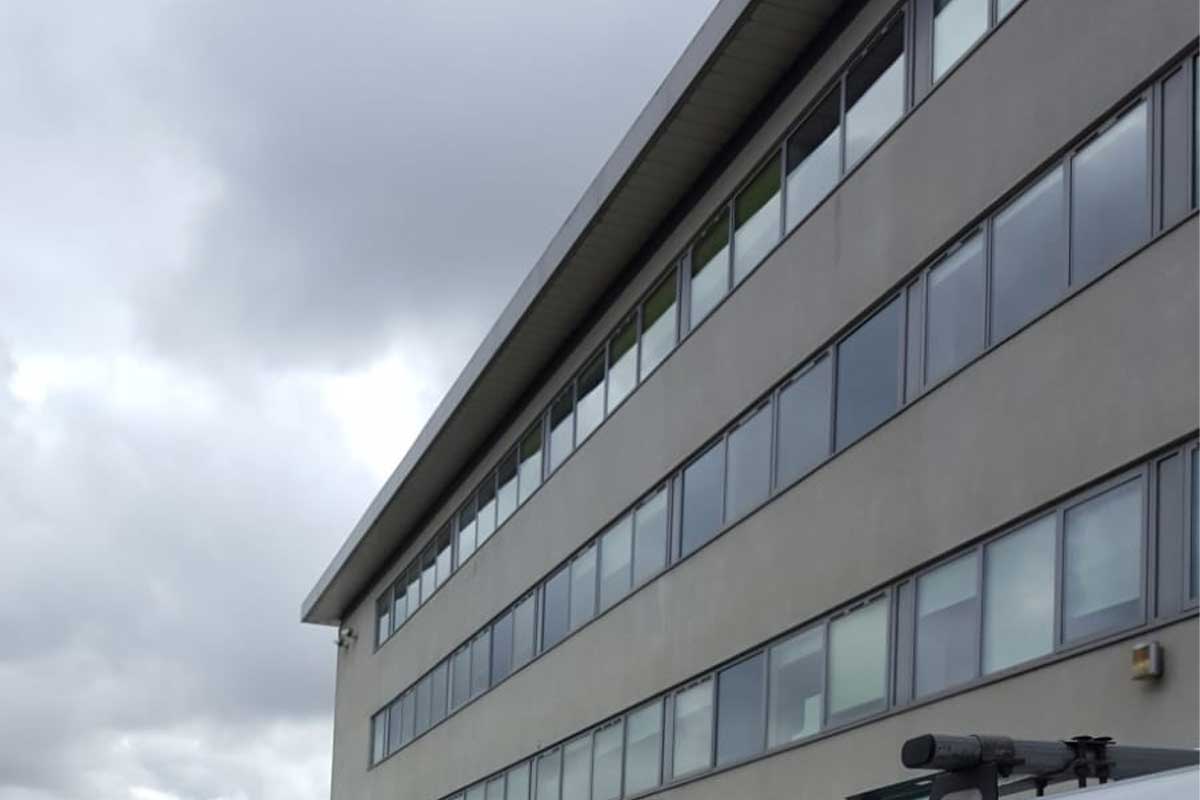 Modern multi-story building with numerous windows, under a cloudy sky, suggesting a chilly atmosphere.